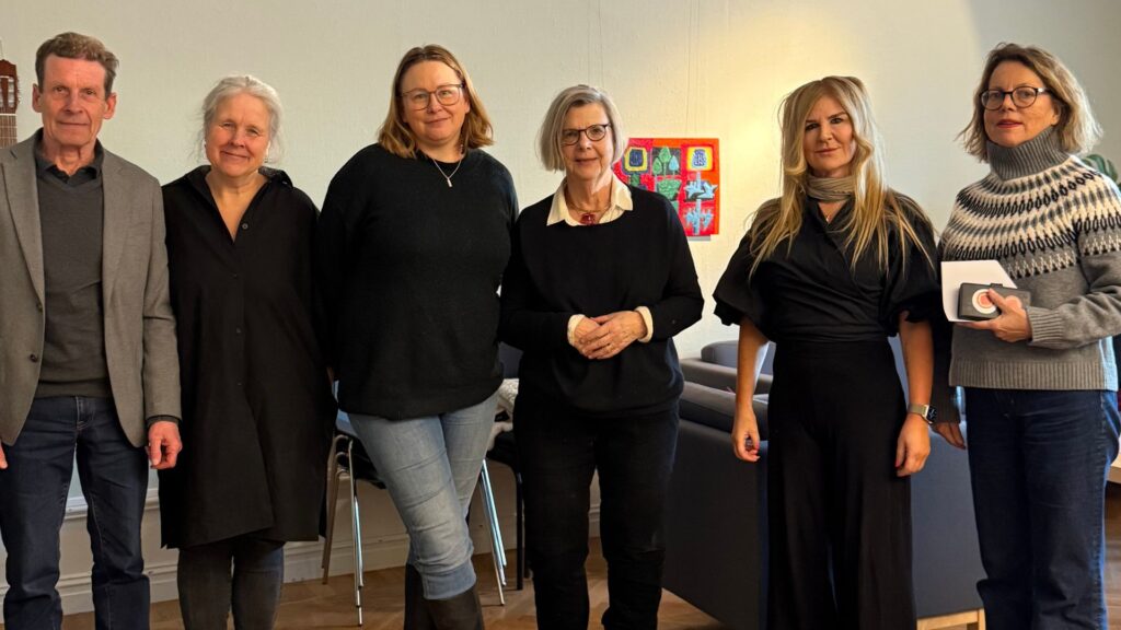 En grupp på sex personer står tillsammans inomhus i en avslappnad miljö.